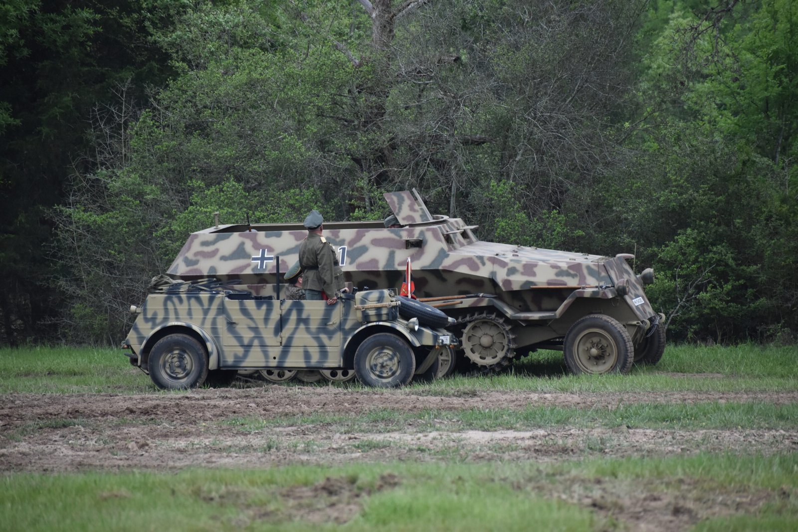 A German officer, standing in his Kubelwagen, consults with his Panzergrenadiers in their Sd. Kfz. 251