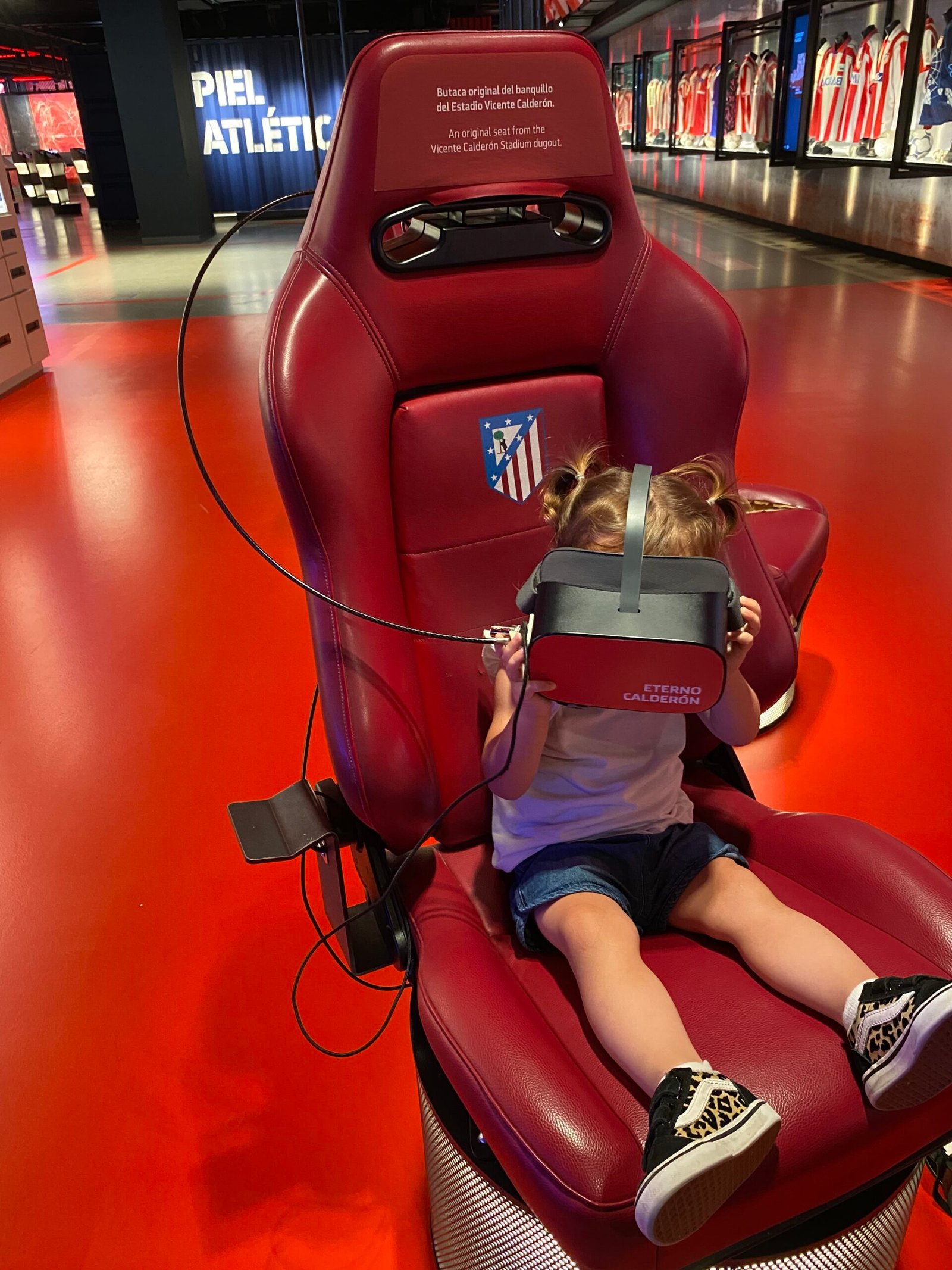 A child wearing virtual reality headset gear inside the Atl&eacute;tico Madrid team museum.